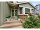 Inviting home entryway with a decorative wreath, potted plants, brick accents, and stone-lined garden at 11245 San Joaquin Rdg, Littleton, CO 80127