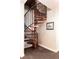 Elegant spiral staircase with hardwood steps and a black metal railing at 24360 E Glasgow Dr, Aurora, CO 80016