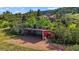 Property features a red barn, surrounded by lush greenery and a picturesque landscape at 1380 Oak Valley Rd, Sedalia, CO 80135
