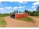 Exterior view of a barn with red siding, a covered area, and a well-maintained yard at 1380 Oak Valley Rd, Sedalia, CO 80135