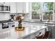 Bright kitchen with white cabinets, stainless appliances, island with seating, and backyard view at 9220 Yucca Way, Thornton, CO 80229