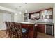 Home bar with dark wood cabinetry, granite countertop, and bar seating for entertainment at 7837 Aravon Ct, Lone Tree, CO 80124