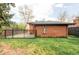 Spacious backyard with a well-maintained lawn, brick house, and fenced area at 121 S Ivy St, Denver, CO 80224
