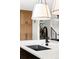 Close up of kitchen island with black sink, modern faucet, and pendant lighting; wood cabinets in the background at 121 S Ivy St, Denver, CO 80224