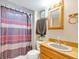 Clean bathroom with shower/tub, wood vanity, and striped curtain at 1466 Elmwood Ln, Denver, CO 80221