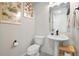 Bright bathroom featuring herringbone tile accent wall, pedestal sink, and elegant botanical wall art at 10105 Morrison Rd, Lakewood, CO 80227