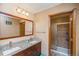 Bright bathroom with double sinks, granite countertops, a wooden framed mirror, and glass shower at 155 Xenon St # 33, Denver, CO 80228