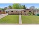 Well-maintained home featuring a cozy front porch and lush green lawn at 1195 S Kendall St, Lakewood, CO 80232