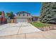 Two-story home with blue siding, brick accents, a two-car garage, and mature landscaping at 9442 W Walden Ave, Littleton, CO 80128