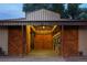 Interior view of the barn, featuring stalls with wooden doors and ample space for livestock, with brick flooring at 7130 Independence St, Arvada, CO 80004