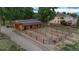 Aerial view of a horse barn with multiple stalls and a fenced outdoor corral area at 7130 Independence St, Arvada, CO 80004