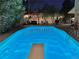 Outdoor pool at night with diving board, surrounded by patio and lush garden under string lights at 7552 Miller Ct, Arvada, CO 80005