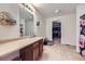 Bathroom featuring a vanity with a sink, a large mirror, and an open doorway to a closet, all on neutral tile flooring at 20530 Randolph Pl, Denver, CO 80249