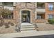 Welcoming condo entrance with stone archway, staircase, and well-kept landscaping at 8083 W 51St Pl # 203, Arvada, CO 80002
