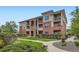 Attractive multi-story condo building with stone accents, manicured lawns, and lush landscaping at 8083 W 51St Pl # 203, Arvada, CO 80002