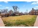 A large front yard sits in front of a brick apartment building on a sunny day at 6002 E 29Th Ave, Denver, CO 80207