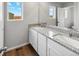Bright bathroom featuring a double sink vanity with granite countertop, white cabinets, and natural light at 2235 Alyssa St, Fort Lupton, CO 80621
