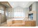 Elegant bathroom featuring a glass enclosed shower, soaking tub, and cozy fireplace at 924 Glen Oaks Ave, Castle Pines, CO 80108