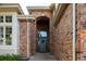 Inviting front entrance featuring a solid wood door, brick archway, and covered porch, creating a warm welcome at 924 Glen Oaks Ave, Castle Pines, CO 80108