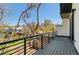 Wide balcony with metal railings that overlook a grassy area, trees, and neighborhood homes on a clear day at 5240 N Raleigh St, Denver, CO 80212