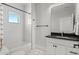 Bright bathroom with black countertop vanity, white-tiled shower and black and white tiled floors at 5240 N Raleigh St, Denver, CO 80212