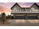 Modern townhome with a brick facade, black trim, two-car garage, and a large driveway at dusk at 5240 N Raleigh St, Denver, CO 80212