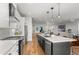 Modern kitchen featuring white cabinets, hardwood floors, designer backsplash, and a large island with pendant lighting at 5240 N Raleigh St, Denver, CO 80212