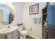 Well-lit half bathroom with a decorative round mirror, floating sink, and painted black storage at 7080 Simms St # 105, Arvada, CO 80004