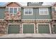 Townhome garages with olive green doors and stone and green siding at 7080 Simms St # 105, Arvada, CO 80004