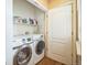 Efficient laundry area with side by side front load washer and dryer with wire rack shelving above at 7080 Simms St # 105, Arvada, CO 80004