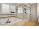 Bright bathroom with a modern soaking tub, walk-in shower with glass door, tile accents, and a window for natural light at 17637 W 87Th Ave, Arvada, CO 80007