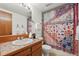 A well-lit bathroom with a wood vanity, tile countertop, and a colorful shower curtain at 501 Manhattan Dr # 202, Boulder, CO 80303
