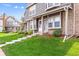 Inviting exterior featuring a well-kept lawn, brick accents, and steps to the townhouse's entrance at 17108 E Whitaker Dr # B, Aurora, CO 80015