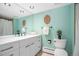 Contemporary bathroom featuring a large mirror, white vanity, toilet, and light green accent wall at 5821 E Ithaca Pl, Denver, CO 80237