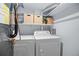 Functional laundry room with modern washer and dryer units and storage shelves at 5821 E Ithaca Pl, Denver, CO 80237
