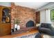 Cozy living room featuring a brick fireplace, hardwood floors, and a comfortable armchair at 5821 E Ithaca Pl, Denver, CO 80237