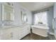 Bright bathroom features a soaking tub, white vanity with double sinks, and wood-look flooring at 4425 Quitman St, Denver, CO 80212