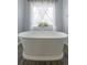 Bright bathroom features a soaking tub in front of a window with sheer curtains at 4425 Quitman St, Denver, CO 80212