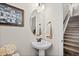 Charming powder room featuring a pedestal sink, oval mirror, and stairway view at 5297 Blue Lunar Ln, Castle Rock, CO 80104