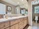 Bathroom featuring a large mirror, double sinks, and light wood cabinets at 9931 E Ida Pl, Greenwood Village, CO 80111