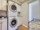 Well-equipped laundry room with stacked washer and dryer, and ample cabinet space at 9931 E Ida Pl, Greenwood Village, CO 80111