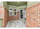 Covered front porch with brick columns and a glass entry door at 25018 E Canal Pl, Aurora, CO 80018