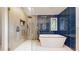 A modern bathroom features a walk-in shower, soaking tub, and stylish blue tile accent wall at 7567 Parkview Mtn, Littleton, CO 80127