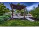 Landscaped backyard with a pergola and chairs next to a stone walkway and trees at 6652 W Asbury Pl, Lakewood, CO 80227
