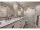 Bathroom with double sinks, marble countertop, patterned tile floor, and glass shower at 6652 W Asbury Pl, Lakewood, CO 80227