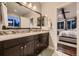 Bathroom featuring a double vanity with dark cabinets, mosaic tile backsplash, and an open view to the main bedroom at 6652 W Asbury Pl, Lakewood, CO 80227
