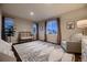 Bedroom with modern crib, large windows, stylish decor, and comfortable seating area on wood floors at 6652 W Asbury Pl, Lakewood, CO 80227