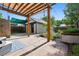 Stone backyard patio featuring a pergola, greenery, a gray garage and a blue and white outdoor rug at 815 S Gaylord St, Denver, CO 80209