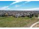 An aerial view reveals the neighborhood homes bordered by vast green space and a walking path on a sunny day at 18995 E Bellisario Creek Pl, Parker, CO 80134