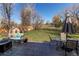 An outdoor patio with comfortable seating and a fire pit overlooks a large grassy backyard with mature trees at 18995 E Bellisario Creek Pl, Parker, CO 80134